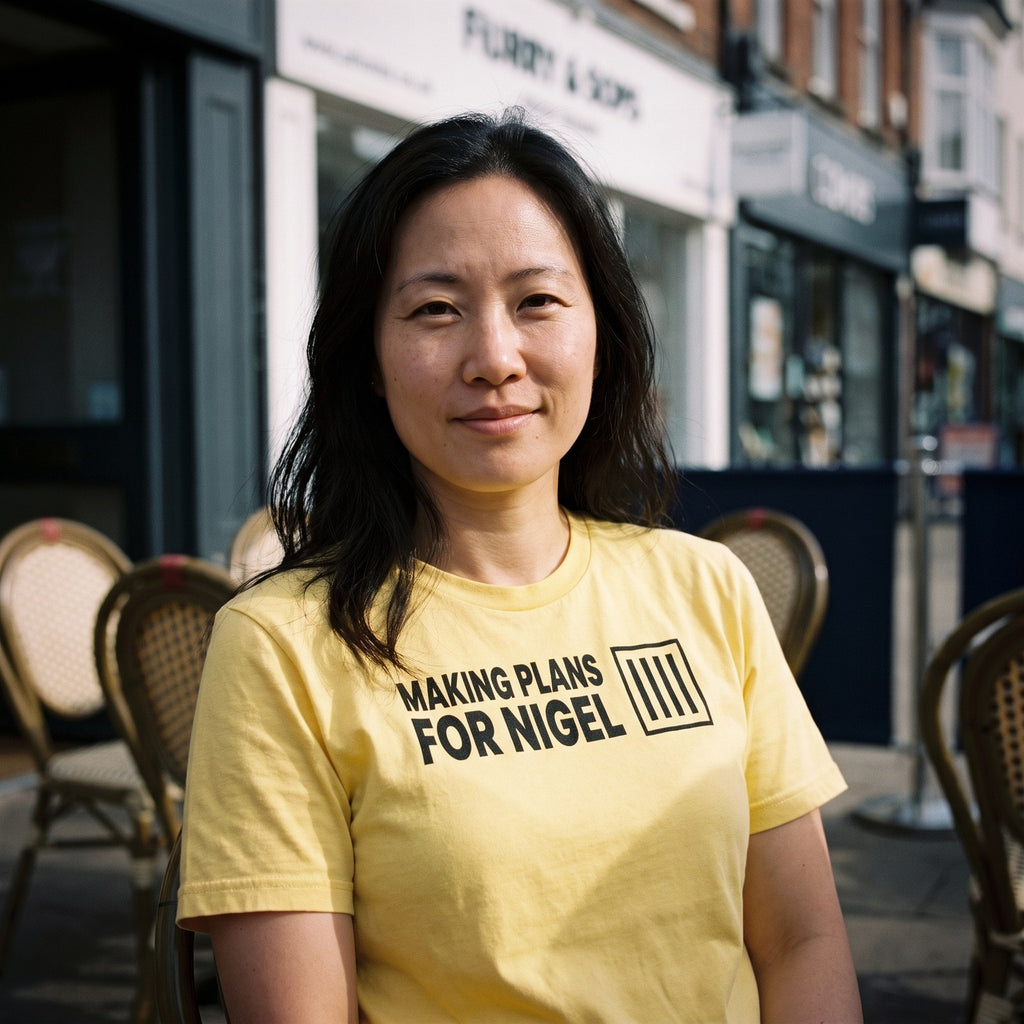 Woman in a yellow Making Plans for Nigel t-shirt on a British cafe terrace