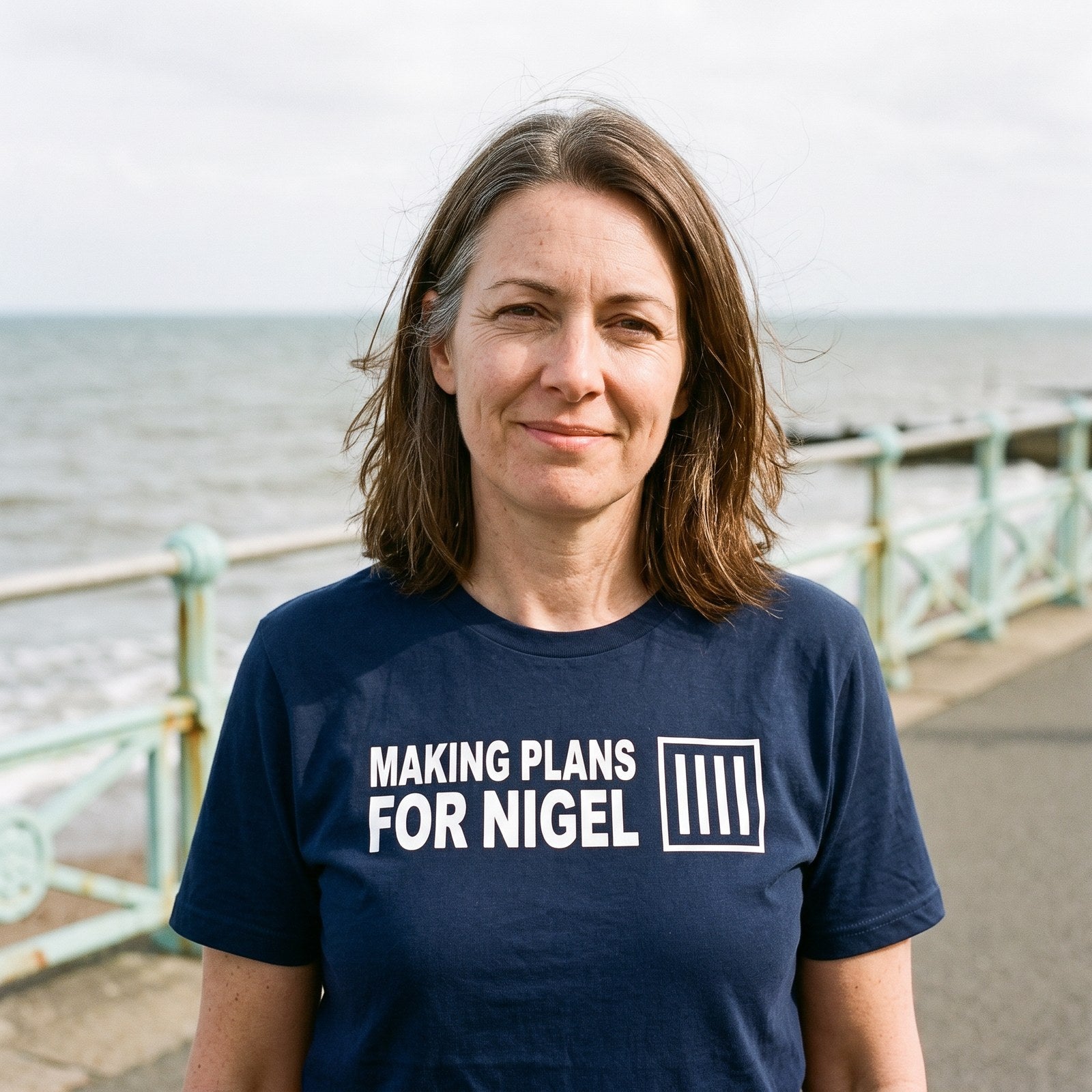 Woman in a navy Making Plans for Nigel t-shirt on an English seaside promenade