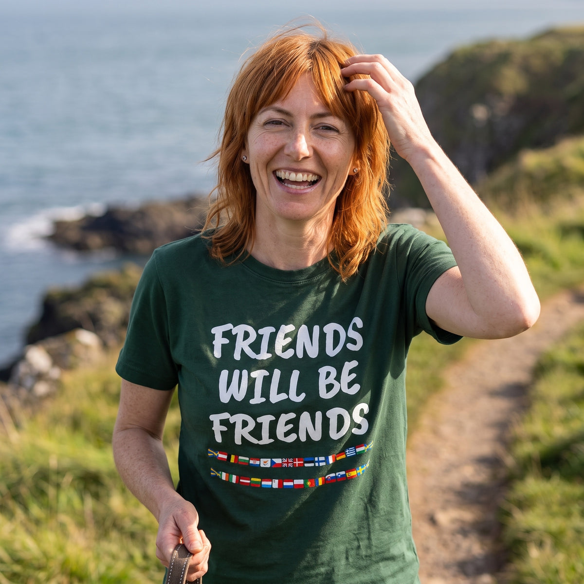 Woman on a coastal walk in a forest green Friends Will Be Friends t-shirt
