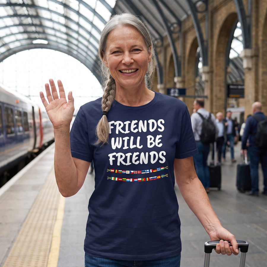 Woman waving on a railway platform in a navy Friends Will Be Friends t-shirt with two strings of European flags