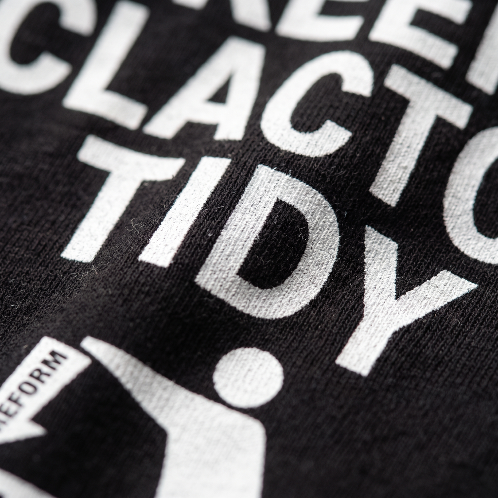 Close up of the white ink Keep Clacton Tidy print on black cotton, showing the fabric weave