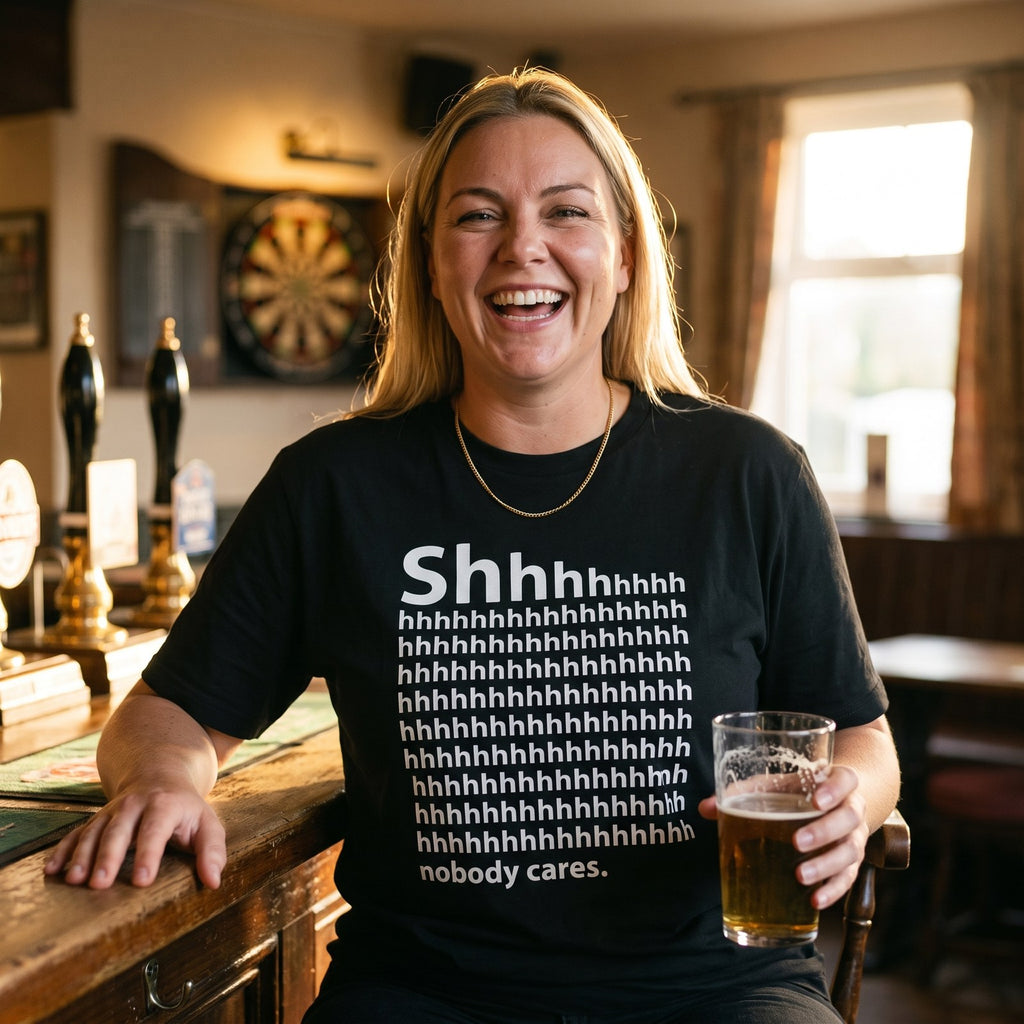 Woman in a black Shhh Nobody Cares t-shirt laughing in a pub