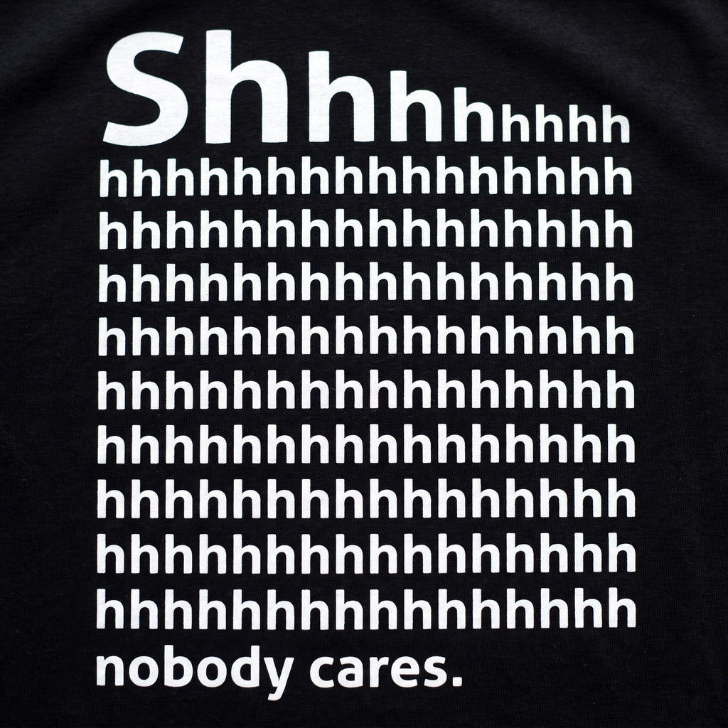 Shhh Nobody Cares print close up, white ink on black cotton