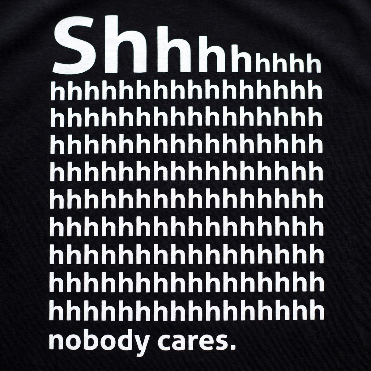 Shhh Nobody Cares print close up, white ink on black cotton