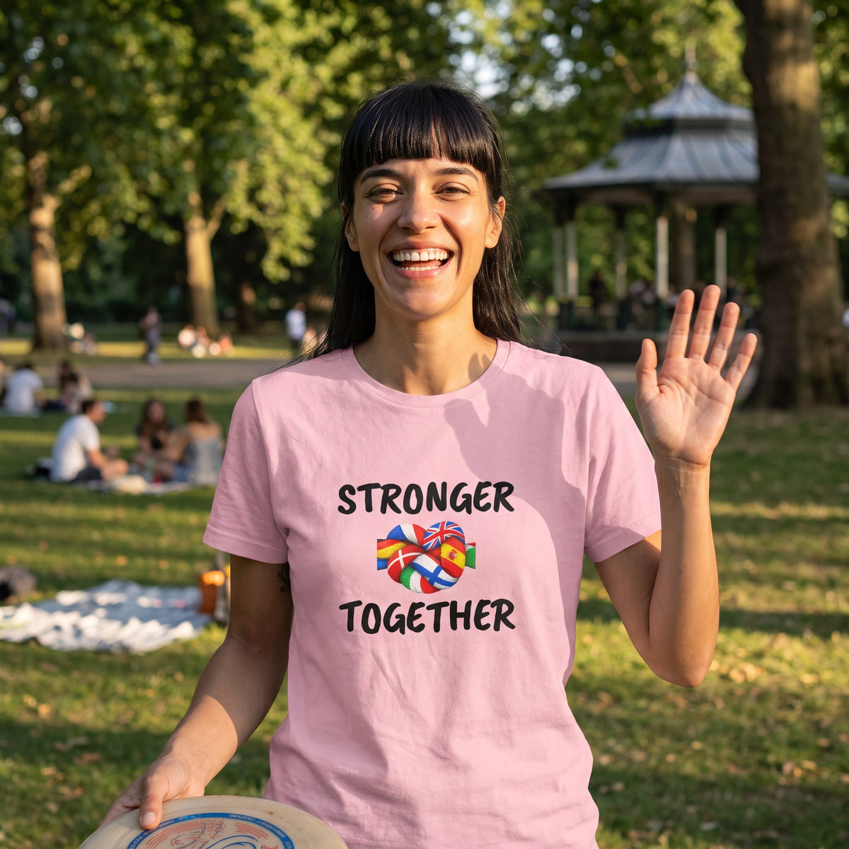 Woman waving in a city park wearing the pink Stronger Together pro-EU t-shirt