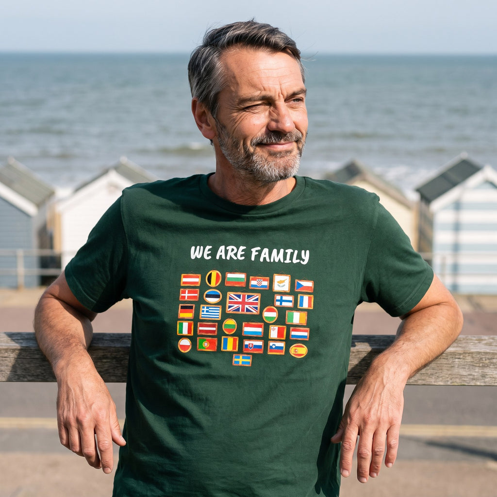 Man leaning on a seaside promenade railing wearing the forest green We Are Family European flags t-shirt, Very Brexit Problems
