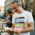 Man with long grey hair and tortoiseshell glasses at a bookshop stall in the white Fascism is Cured by Reading t-shirt, print close up, Very Brexit Problems