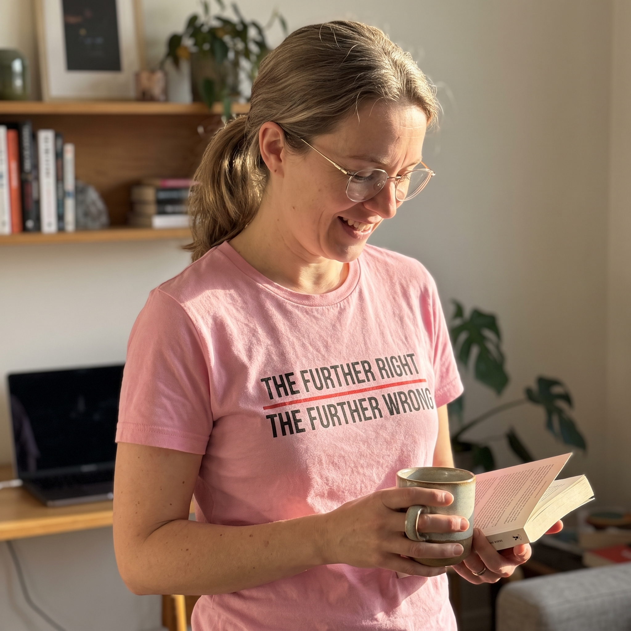 Woman wearing a pink The Further Right, The Further Wrong t-shirt at home