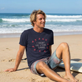 Man sitting on the beach in the navy I Couldn't Give a Flying Flamingo t-shirt, print close and legible, Very Brexit Problems