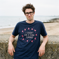 Man in a navy I Couldn't Give a Flying Flamingo t-shirt on a beach beside a low sea wall, Very Brexit Problems